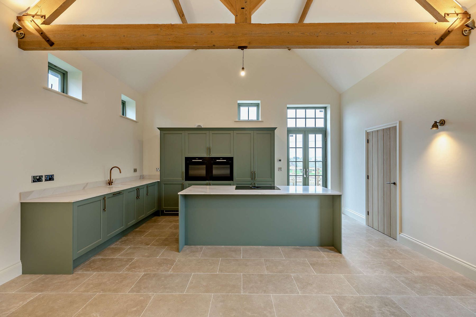 Vaulted kitchen with sage cabinetry and oak trusses
