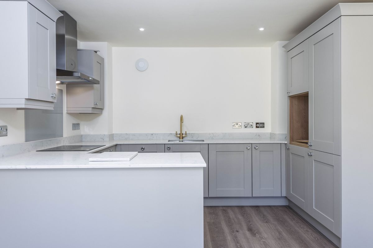Shaker kitchen with quartz worktops and a brass tap