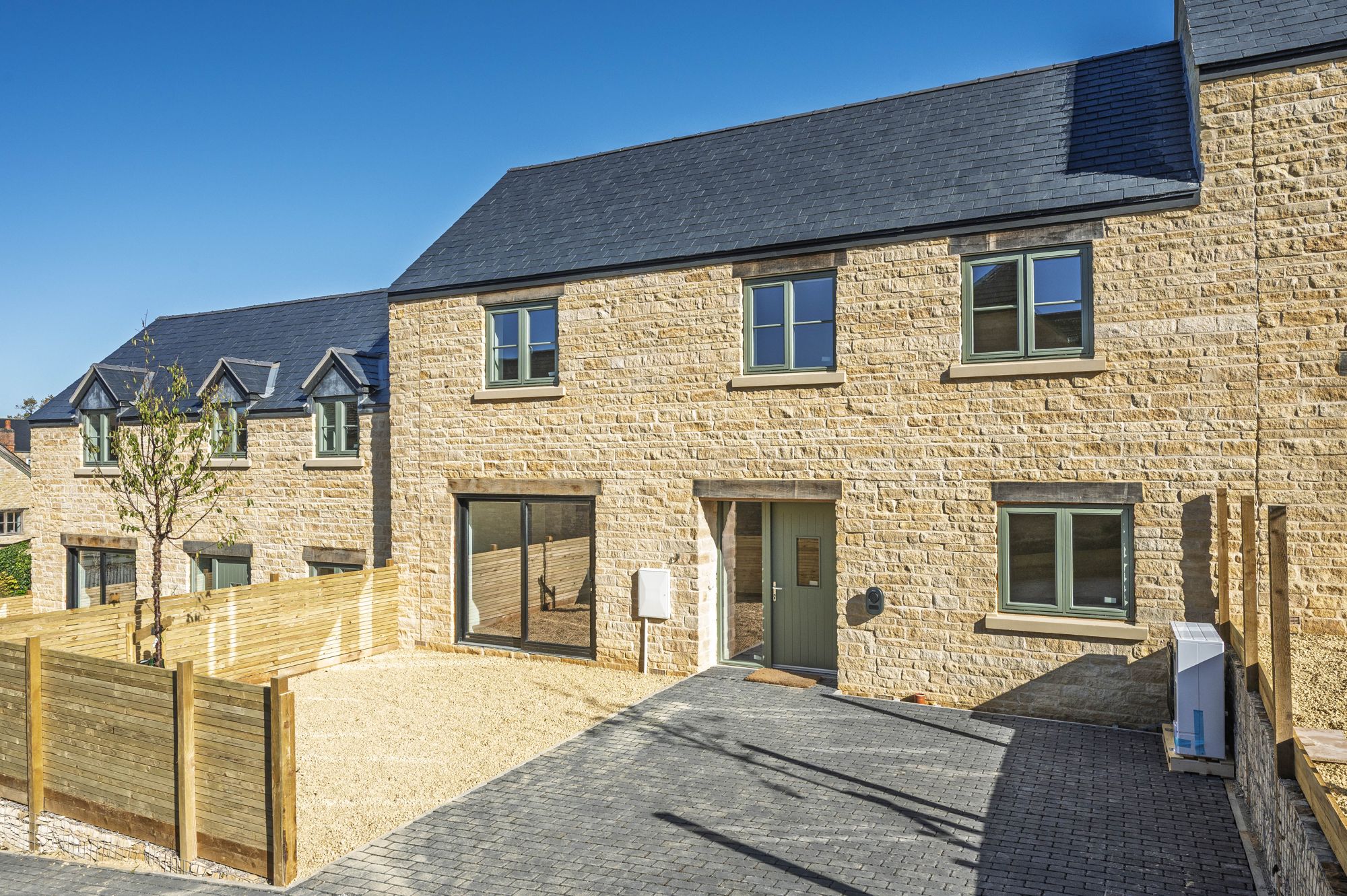 Terrace of new Cotswold stone houses with slate roofs and gravel gardens